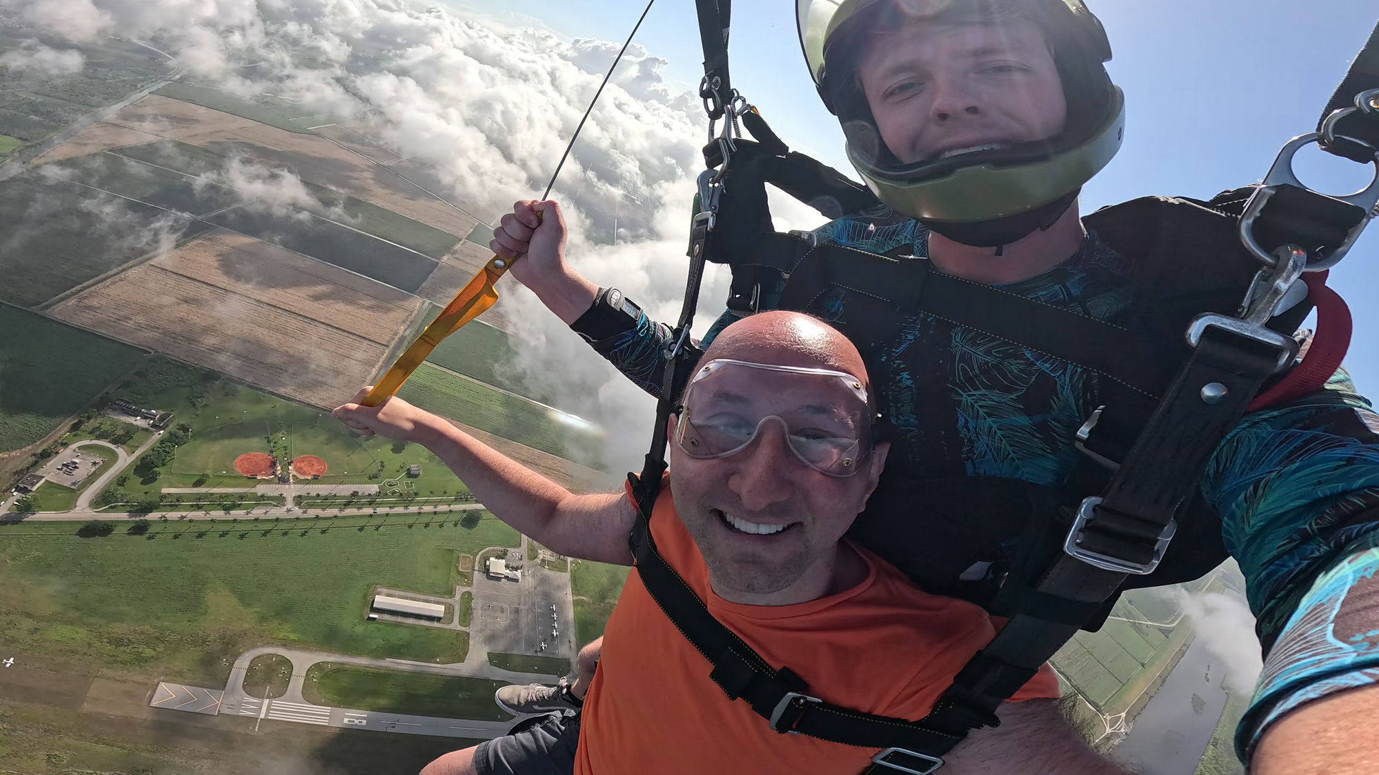 David grinning mid-air on a tandem skydive above South Florida farmland and clouds, March 31, 2025